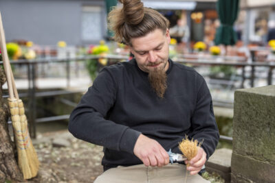 ein Mann arbeitet mit einer Zange an einem kleinen Besen
