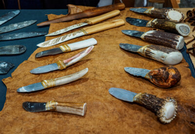 zwei Reihen Messer mit Feuerstein- und anderen Klingen sowie Griffen aus Horn, Knochen und Holz